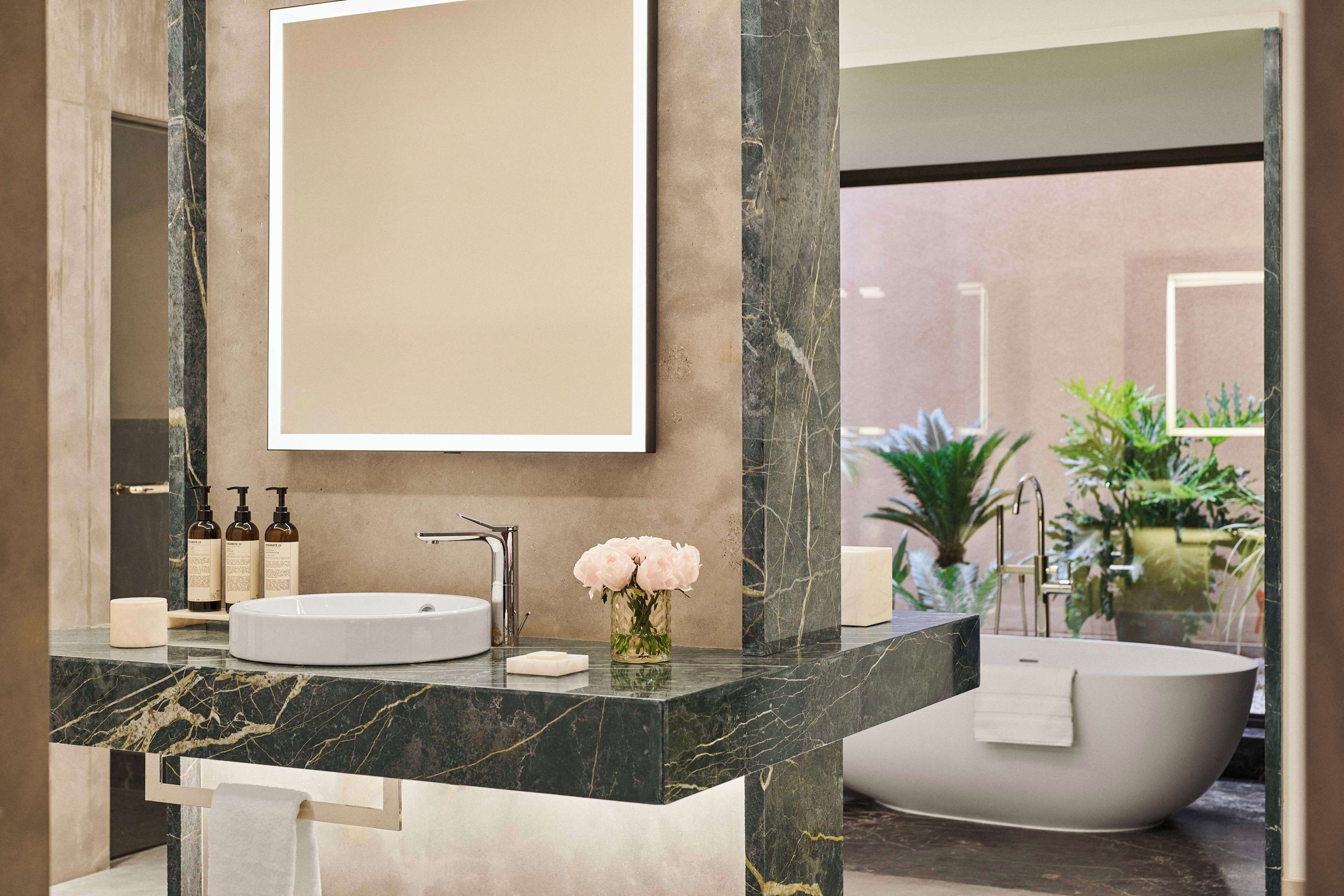 A modern bathroom with a marble vanity, a freestanding bathtub, and a large mirror.