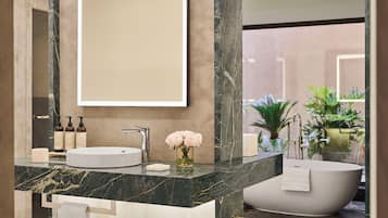 A modern bathroom with a marble vanity, a freestanding bathtub, and a large mirror.
