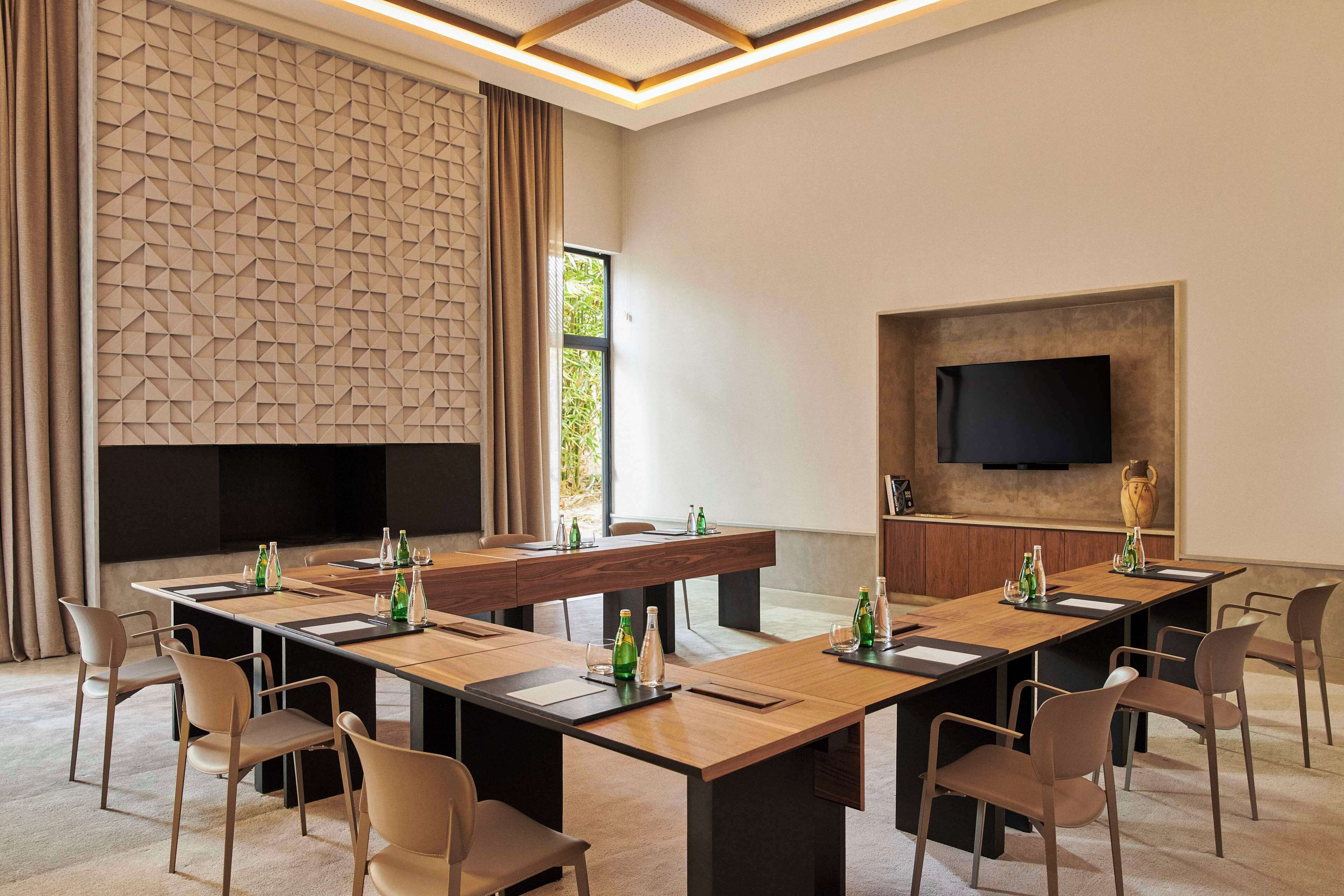 Een vergaderzaal met een lange tafel, stoelen en een flatscreen televisie aan de muur.