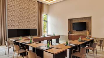 A conference room with a long table, chairs, and a flat-screen TV mounted on the wall.