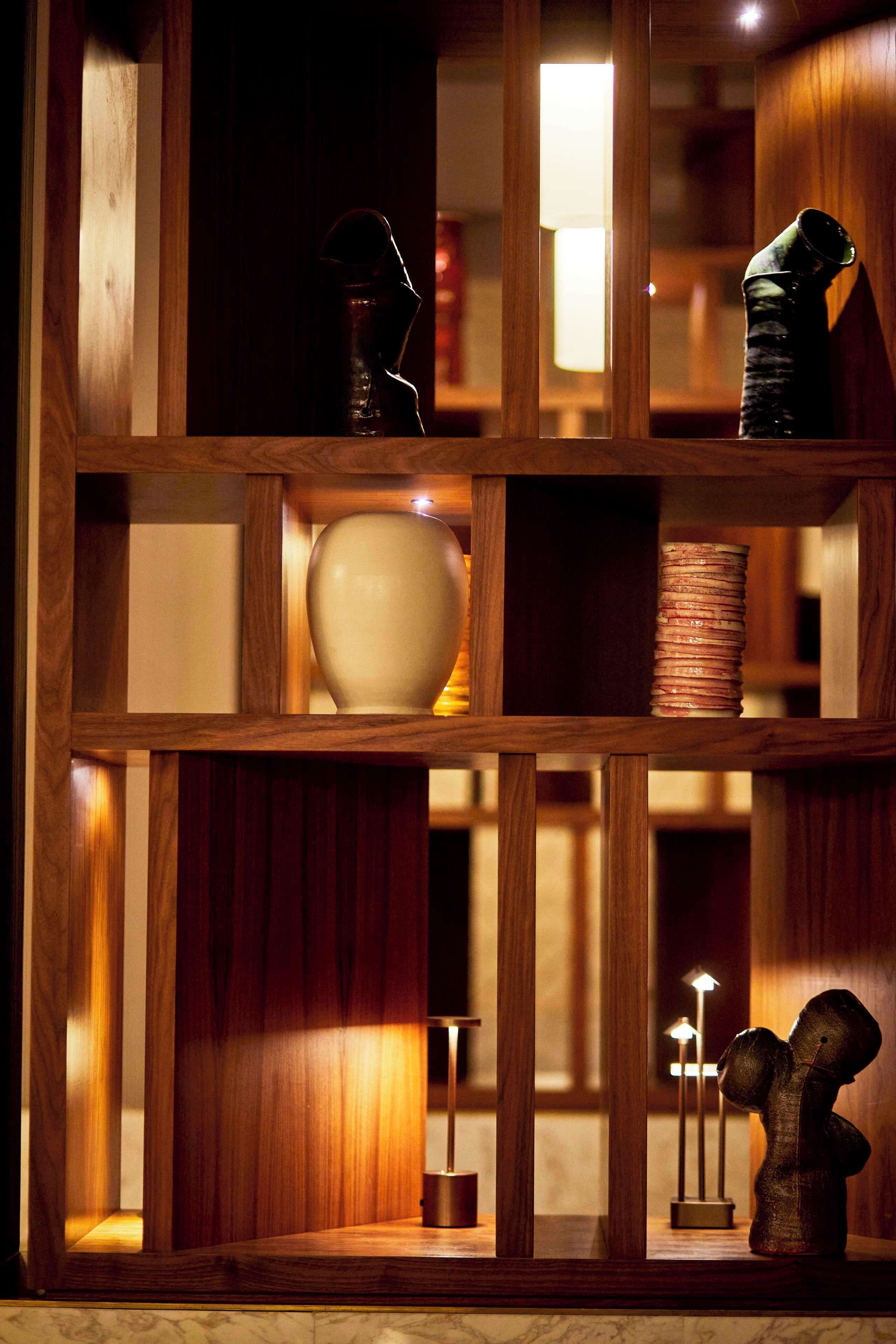 Une étagère en bois sur laquelle sont disposés divers objets, notamment un vase, une bobine de fil et une petite sculpture.