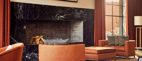 Una sala moderna con chimenea, muebles naranjas y un ventanal grande.