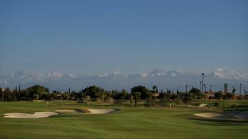 A golf course with a clear view of snow-capped mountains in the background.