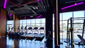 A gym with treadmills, elliptical machines, and weightlifting equipment. - Marco Polo - Pastel Studio with Stunning Aerial City Views (Dubai)