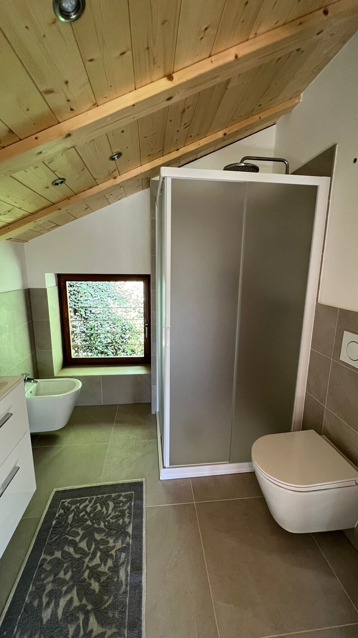 A small, modern bathroom with a shower, toilet, and sink.