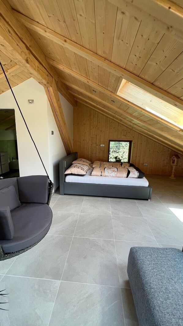 Una habitación espaciosa con techos altos, una cama, un sofá y un ventanal.