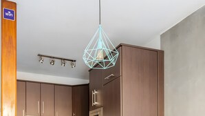 Een moderne keuken met houten kastjes, een witte eettafel en een geometrisch hanglamp.