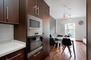 A modern kitchen with built-in appliances, a dining area with a table and chairs, and a view of the outdoors.