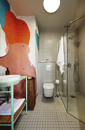 A modern bathroom with a glass shower enclosure, a white toilet, and a sink with a wooden vanity.