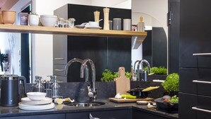 Una cocina moderna con encimera negra, pileta de acero inoxidable y repisa de madera.