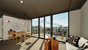 Una sala de estar moderna con un ventanal grande, un sofá, una mesa de centro de madera y un comedor con sillas y una mesa.
