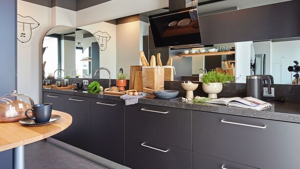 Una cocina moderna con armarios oscuros, una isla grande y un televisor de pantalla plana.
