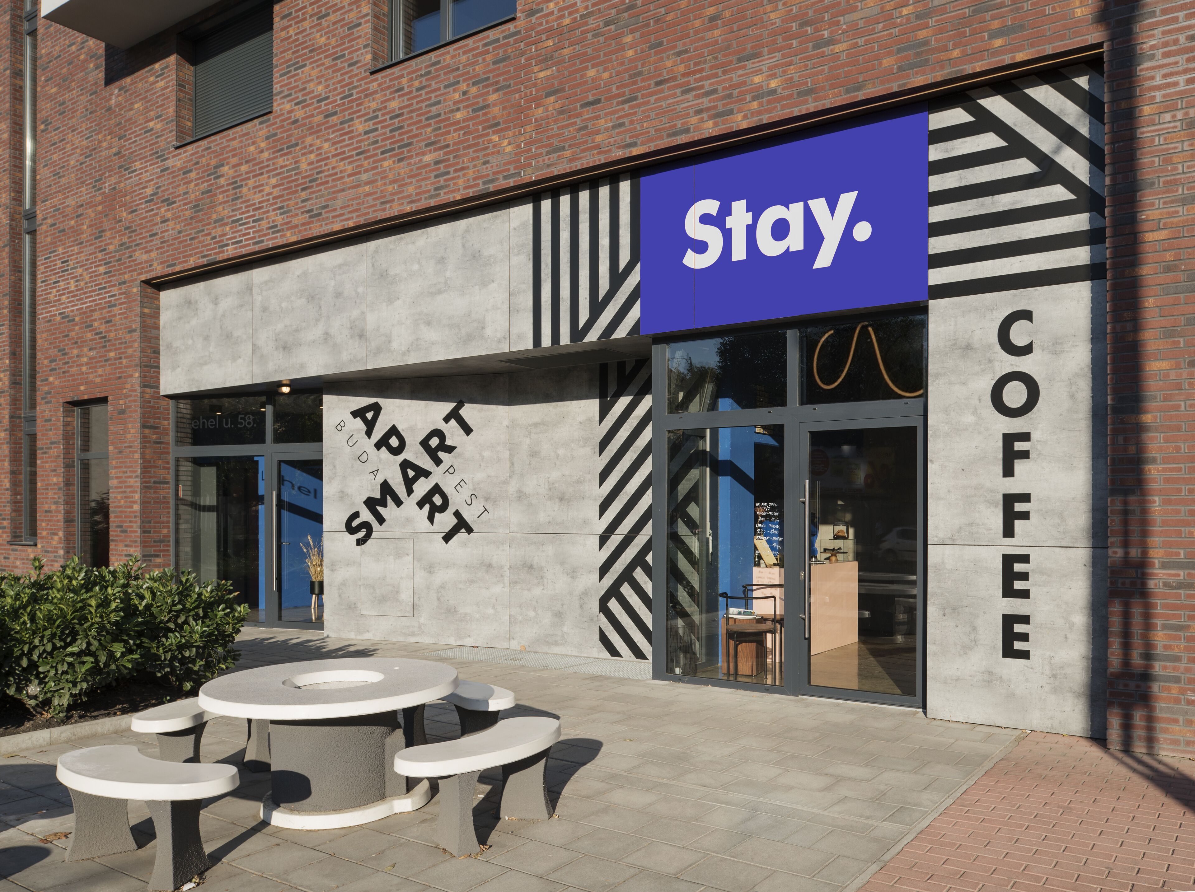 A Stay. Coffee building with a modern design, featuring a prominent 'Stay. Smart' sign and outdoor seating area.