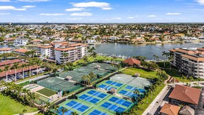 Un resort con varias canchas de tenis, un puerto deportivo y vista al lago.