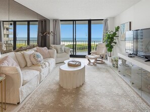 A modern living room with a sofa, armchairs, a coffee table, and a TV.