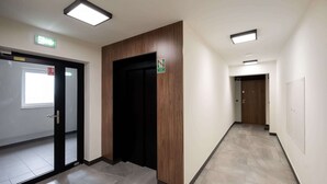 A hallway with a wooden panel wall, a black door, and a sign indicating an exit.