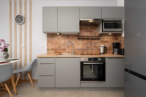 Eine moderne Küche mit grauen Schränken, einer Ziegelrückwand, einer Mikrowelle, einem Backofen und einem Spülbecken.