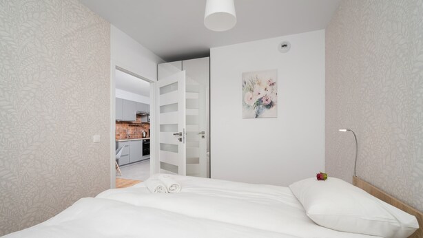 A bedroom with a bed, a painting, a nightstand, and a door leading to a bathroom.