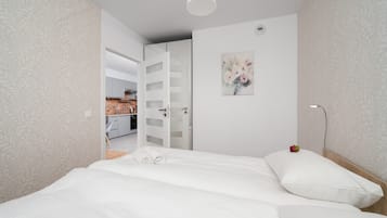Een slaapkamer met een bed, een schilderij, een nachtkastje en een deur naar een badkamer.