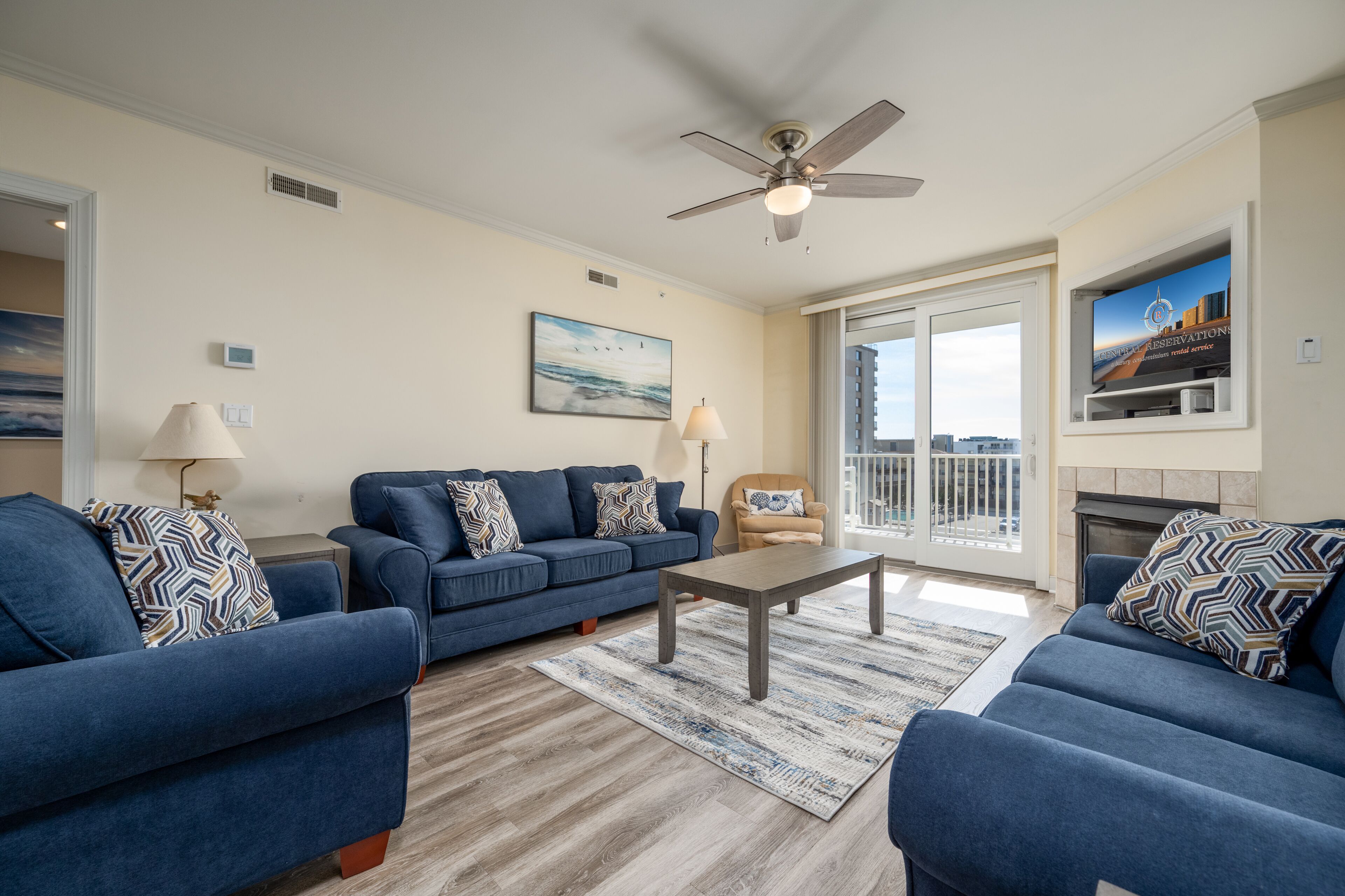 A living room with two blue sofas, a coffee table, and a fireplace.