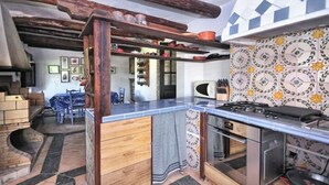 Una cocina con vigas de madera, un salpicadero de azulejos y un horno empotrado.