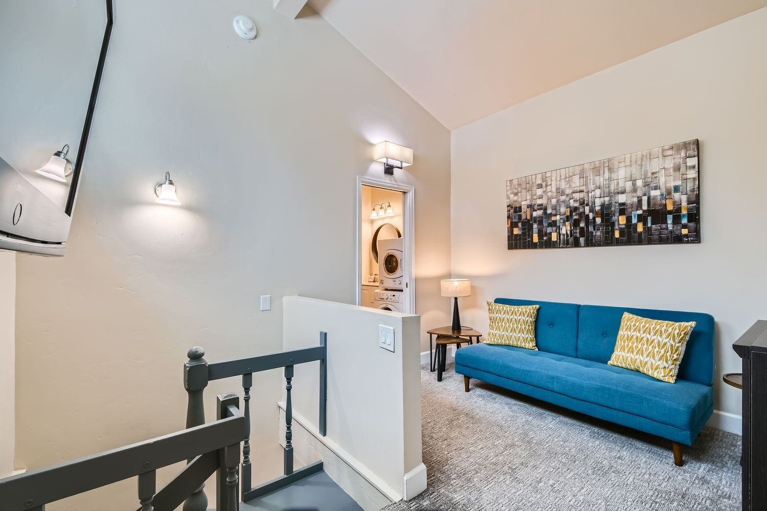 Un salon moderne avec un canapé bleu, une table basse et un tableau accroché au mur.