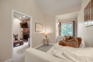 Un dormitorio con cama, chimenea, ventana y puerta que da a otra habitación.