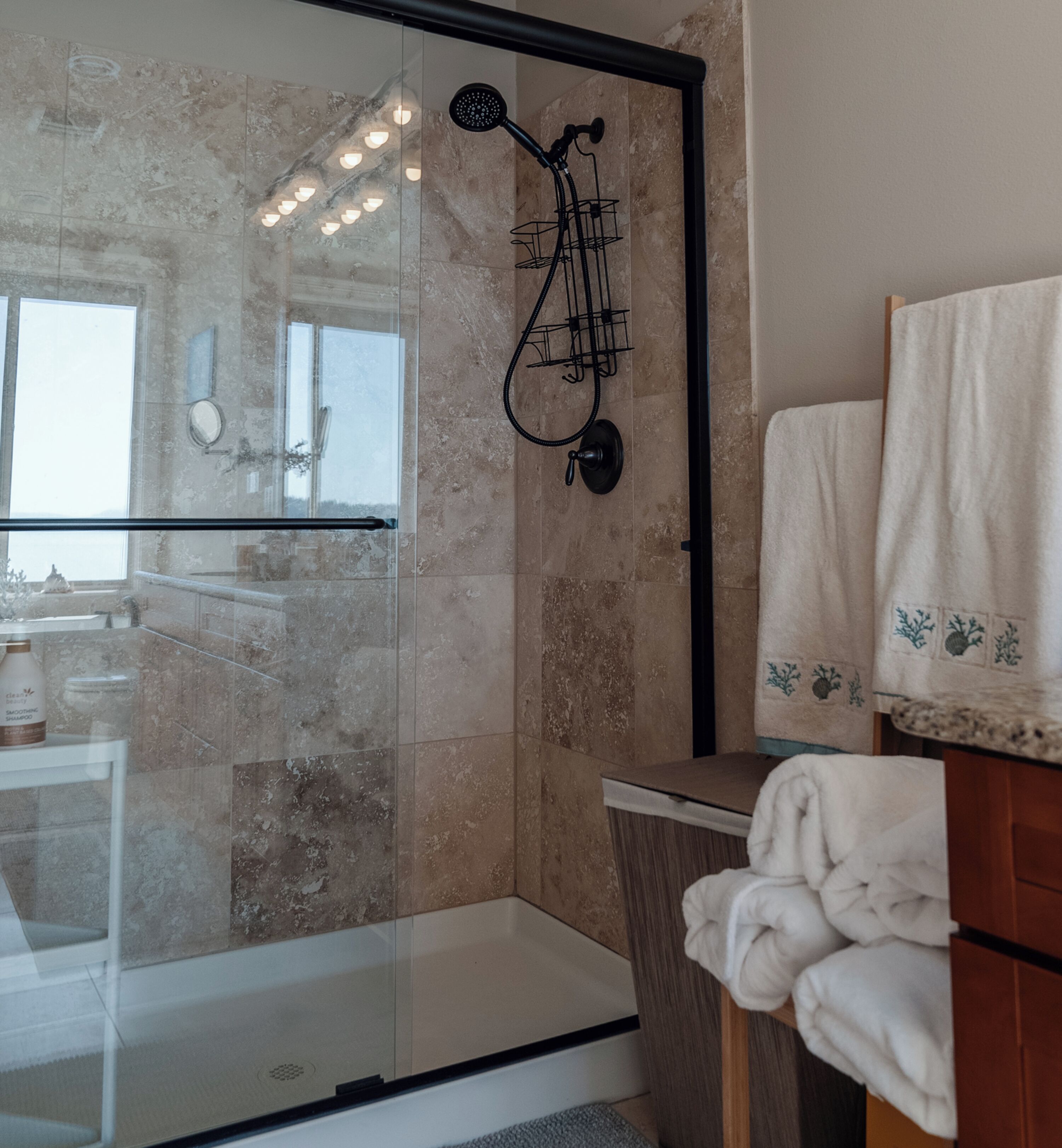 A modern bathroom with a glass shower enclosure, a wooden vanity, and a towel rack.