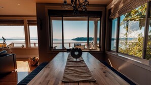 A dining area with a wooden table, a rug, and a view of the sea. - Stunning House with Views of Puget Sound Ideal for Family Reunions (Edmonds)