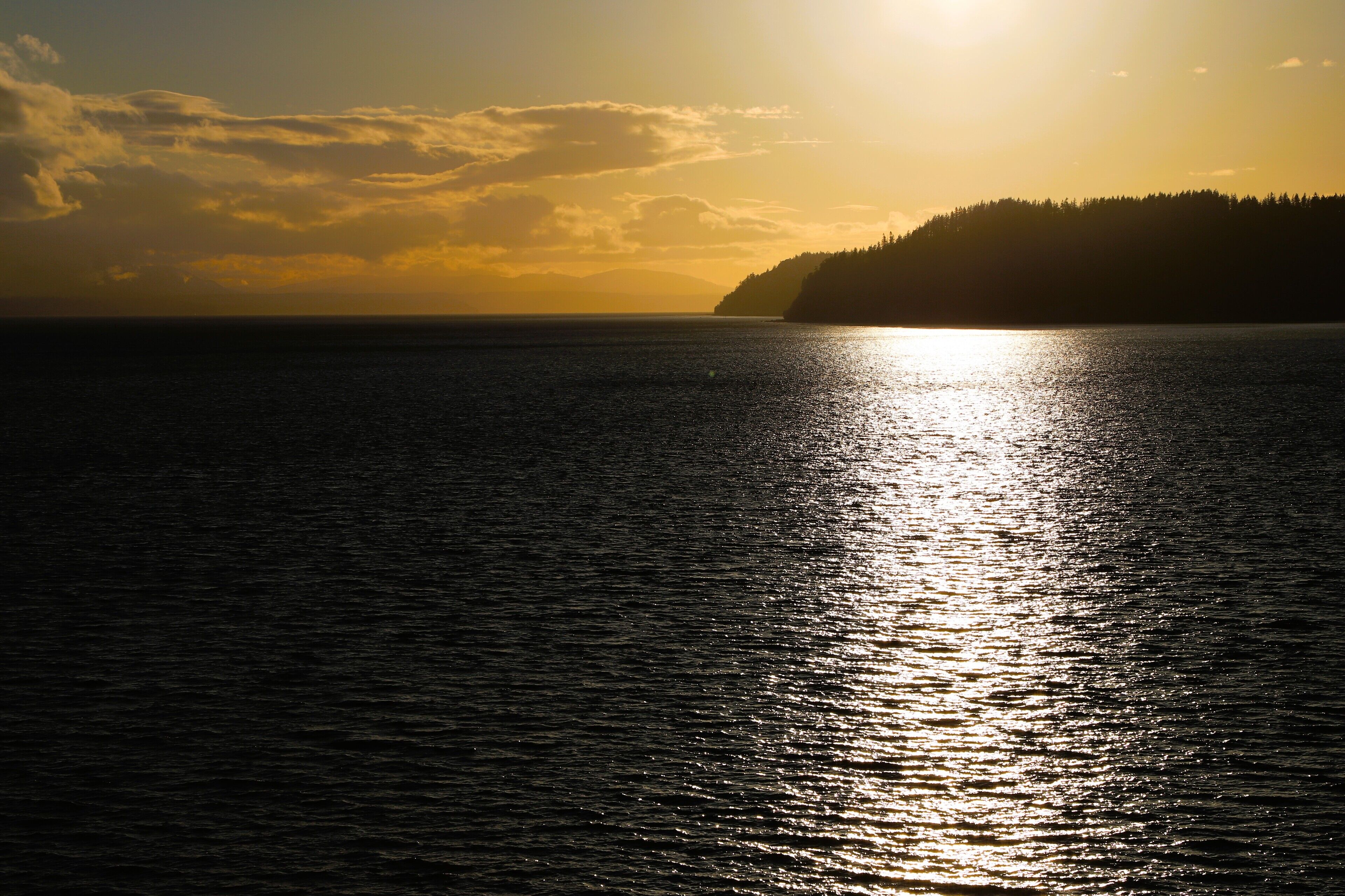A sunset over a calm sea with a distant landmass.