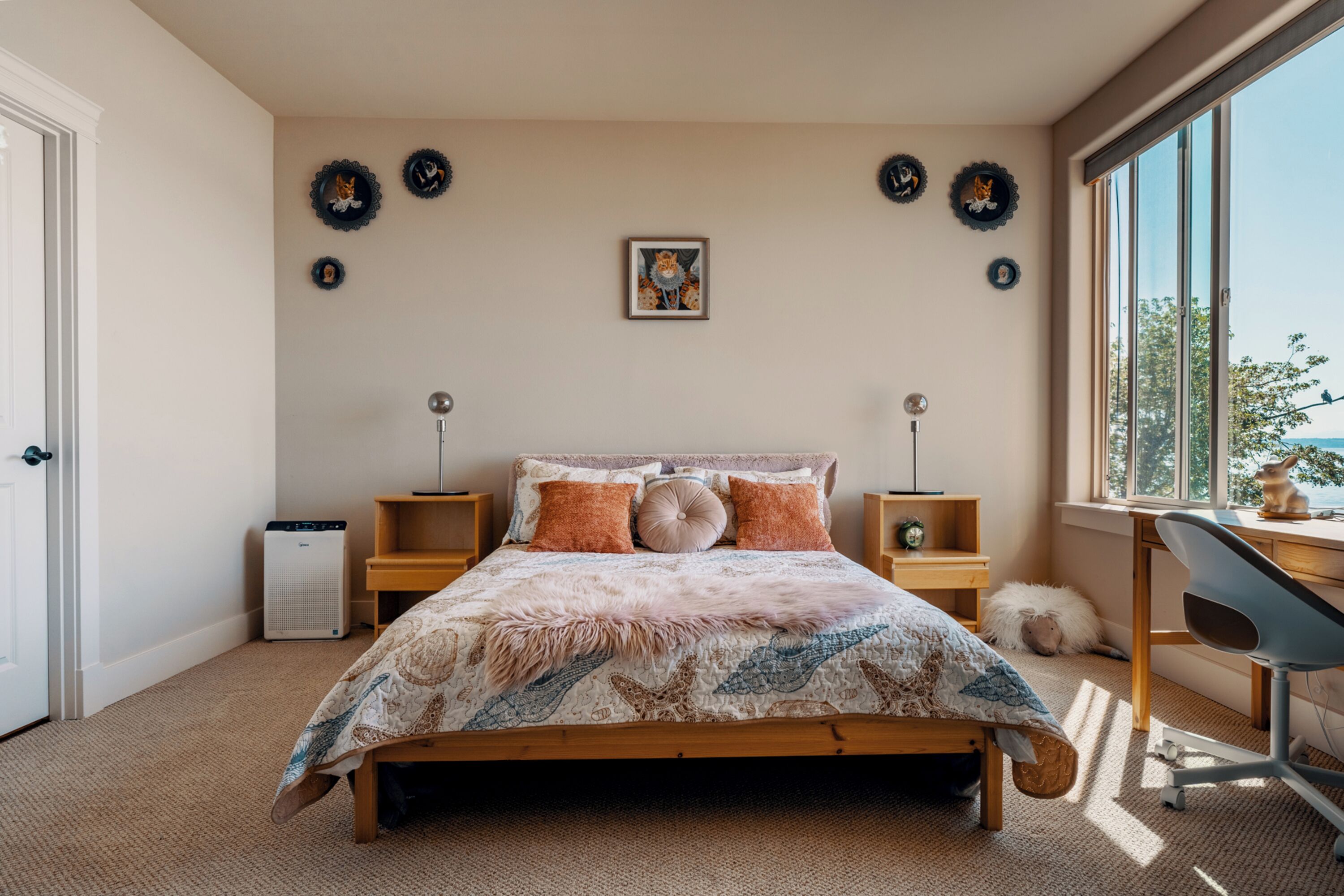 A bedroom with a bed, a desk, and a chair. There are wall decorations and a window with a view.
