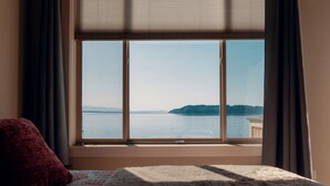 A room with a large window overlooking a body of water and a distant landmass. - Stunning House with Views of Puget Sound Ideal for Family Reunions (Edmonds)