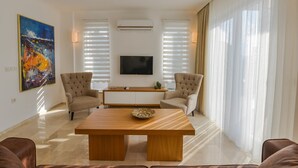 Un salón moderno con una mesa de centro de madera, dos sillones, un televisor de pantalla plana y un cuadro en la pared.