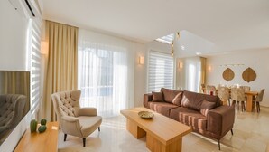 Una sala de estar moderna con sofá, sillón, mesa de centro y comedor con sillas y mesa.