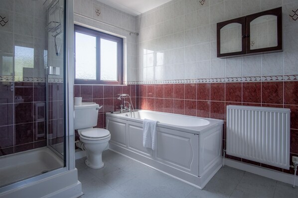A bathroom with a toilet, bathtub, and shower. - Avoca - 3 Bedroom - Llangennith (Swansea)