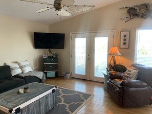 Relax in this inviting living space with a flat-screen TV, comfortable seating, and a sliding door to an outdoor area.