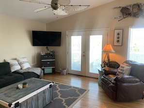 Relax in this inviting living space with a flat-screen TV, comfortable seating, and a sliding door to an outdoor area.