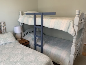 Cozy bedroom with a bunk bed setup featuring a ladder and striped bedding, complete with a bedside table and nightstand.
