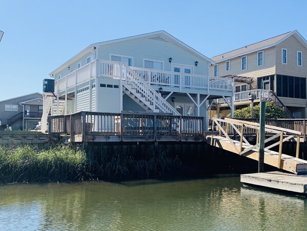 Enjoy waterfront views from the spacious balcony and deck, accessible via a staircase, with a dock extending into the water.