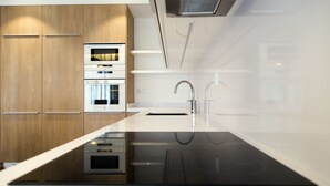 A modern kitchen with a central island, built-in oven, and stainless steel appliances. - Apartamentos Turísticos da Nazaré (Nazaré)