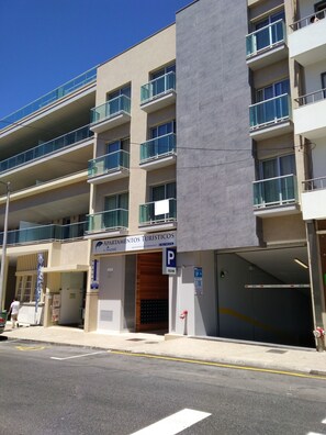 A multi-story building with balconies, a parking sign, and a sign for 'Apartamentos Turísticos'. - Apartamentos Turísticos da Nazaré (Nazaré)