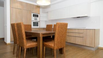 Una cocina moderna con armarios de madera, horno empotrado y una mesa de comedor con cuatro sillas.