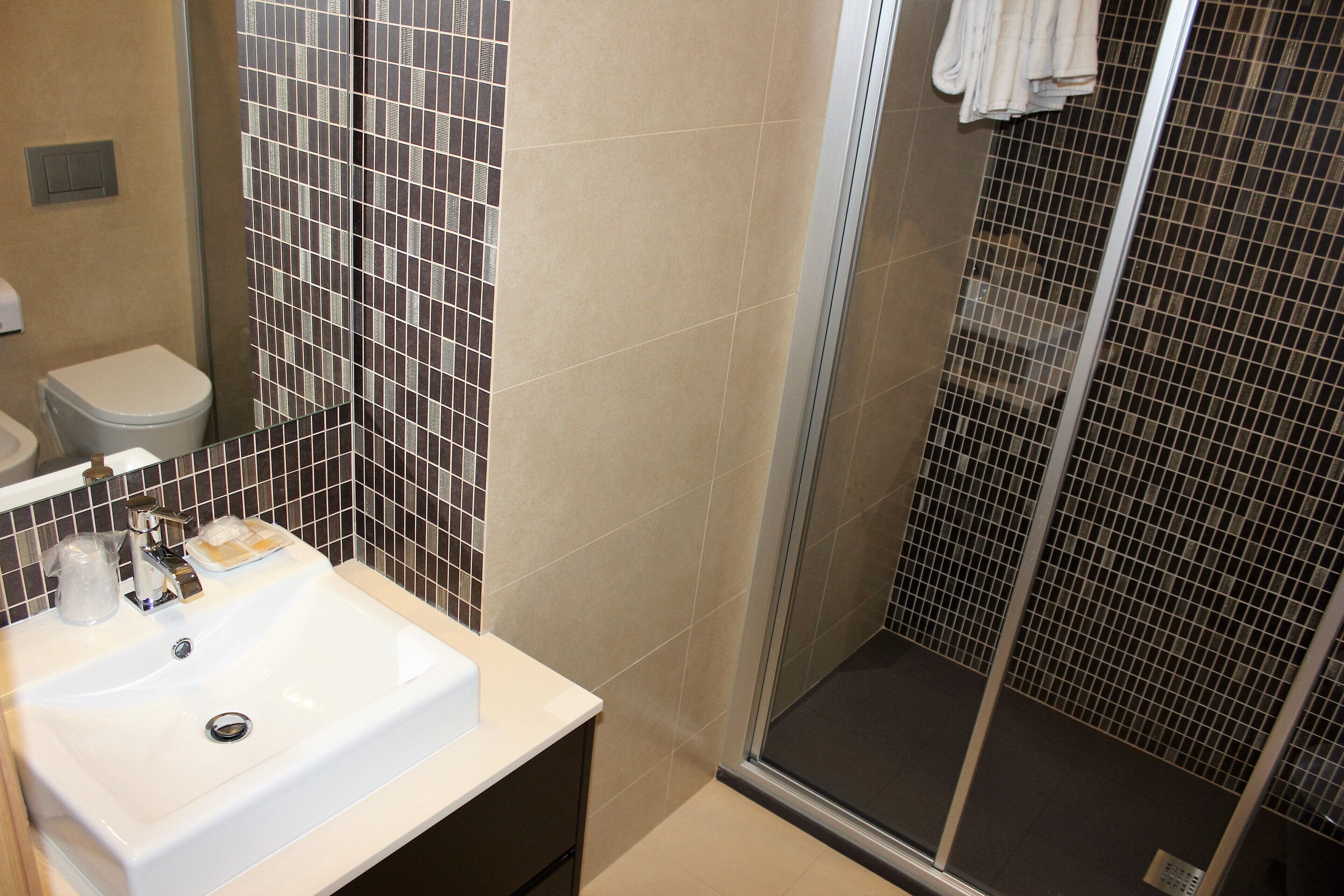 A bathroom with a white sink, a toilet, and a glass shower enclosure.