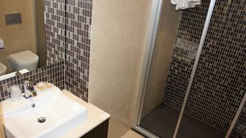 A bathroom with a white sink, a toilet, and a glass shower enclosure.