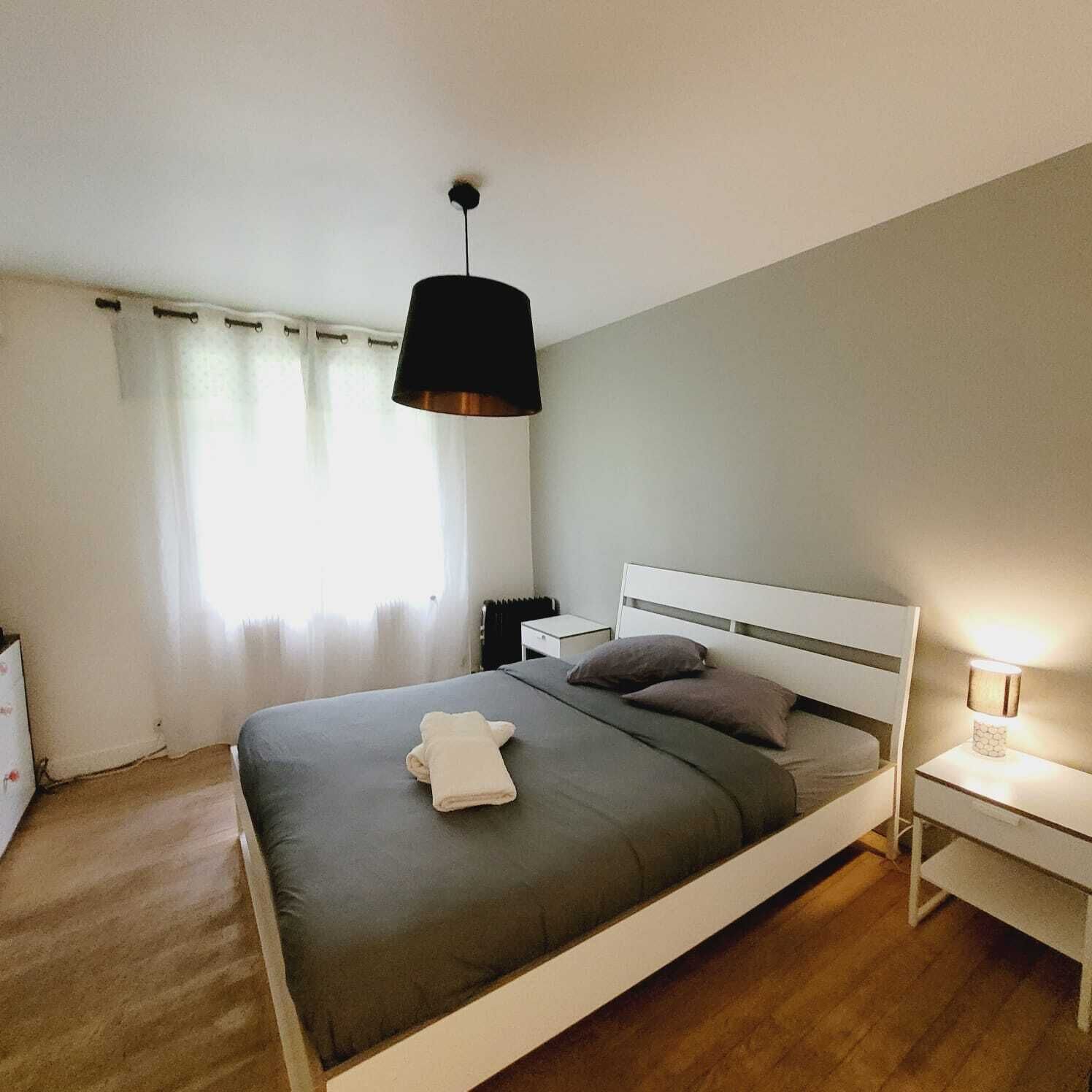 Ein modernes Schlafzimmer mit einem Einzelbett, einem Nachttisch, einer Lampe und einem Fenster mit Vorhängen.