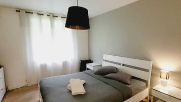 Ein modernes Schlafzimmer mit einem Einzelbett, einem Nachttisch, einer Lampe und einem Fenster mit Vorhängen.