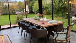 A modern dining area with a glass ceiling, a wooden table, and several chairs.
