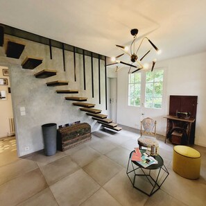 Un intérieur moderne agrémenté d’un escalier, d’une machine à coudre ancienne et d’une chaise aux lignes géométriques.