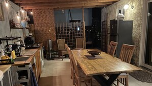 A cozy dining area with a wooden table and chairs, a kitchen area with a coffee machine, and a view of the outside. - *LUXURIOUS 2 person STUDIO* (Noord)