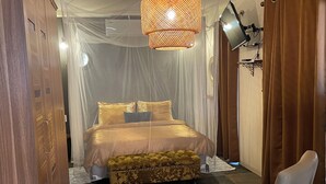 A bedroom with a bed, a chair, and a round rug. - *LUXURIOUS 2 person STUDIO* (Noord)